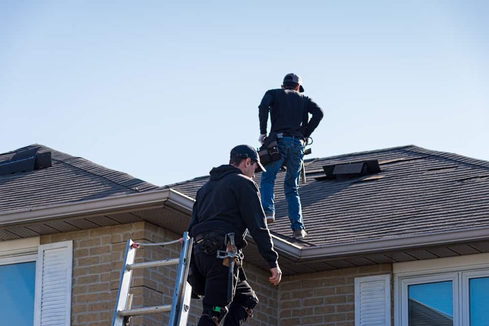 two roofing contractors working on a roof.