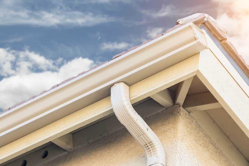 Close-up view of new gutter installation on a residential home with clear skies in the background